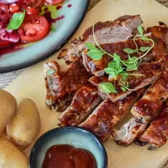 Saftiga revben, perfekt grillade och glaserade, serveras med färsk potatis och en tomat- och löksallad. En härlig måltid att grilla revben till!