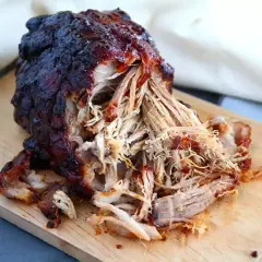 Saftigt, mörkt pulled pork på en skärbräda. Perfekt temperatur för att dra isär köttet.
