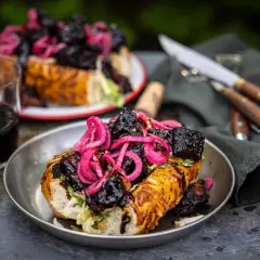 En saftig amerikansk barbeque-smörgås med möra köttbitar och picklad rödlök, serverad med rödvin.