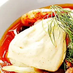 En närbild på en skål med räkor, dill och en generös klick egen aioli.