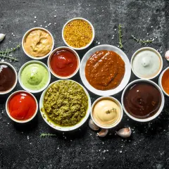 Olika såser i skålar, perfekt för att hitta inspiration till ditt eget barbequesås recept. Här finns allt från röd ketchup till grön pesto.