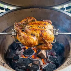 Hel kyckling grillas på rotisserie över glödande kol. En gyllene, saftig kyckling som doftar underbart.