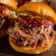 Saftig pulled pork-burgare med krispig coleslaw och en generös klick BBQ-sås. Perfekt sås till pulled pork!