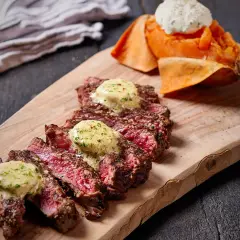 Skivad entrecote rare med smält örtsmör, serverad med sötpotatis och en klick gräddfil.