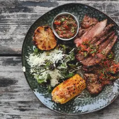 Skivad iberico-stek med perfekt temperatur, serverad med grillad majskolv, citron och en fräsch salsa.
