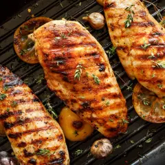 Grillade kycklingbröst med citron och vitlök på en grillpanna. Perfekt för att grilla kycklingvingar en solig dag.