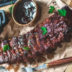 Glacerade revben, redo att grillas, serveras med BBQ-sås och coleslaw. Att koka revben innan grillning ger extra saftighet.