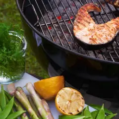 Grilla lax på kolgrill med färska grönsaker och citron. En härlig sommarmåltid.