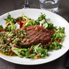 Grillad picanha styckdetalj serverad med en fräsch sallad och chimichurrisås.