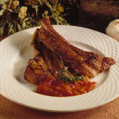 Saftiga, tjocka revben med en smakrik tomatsalsa och en vitlöksklyfta som dekoration.