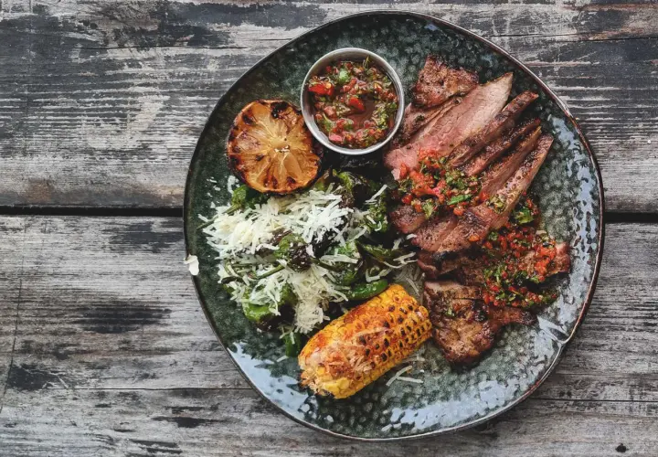 En tallrik med saftigt grillat secreto iberico, serverat med grillad majskolv, citron och en fräsch salsa. Ett perfekt secreto iberico recept för en festmåltid.