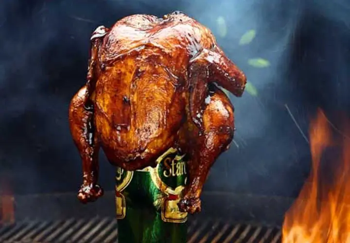 En saftig ölkyckling, perfekt grillad med gyllene skinn, står stolt på en ölburk. Rök och flammor skapar en dramatisk bakgrund.