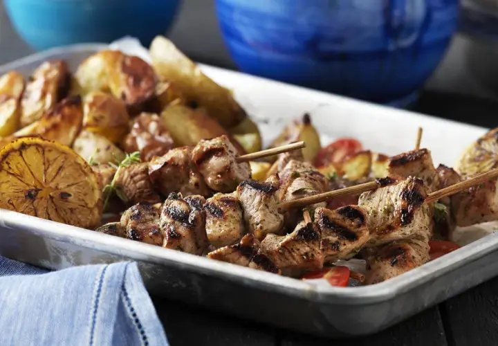 Grillade spett med fläskkött, rostade potatisar och citronklyftor. Perfekt med en god souvlaki krydda för extra smak.