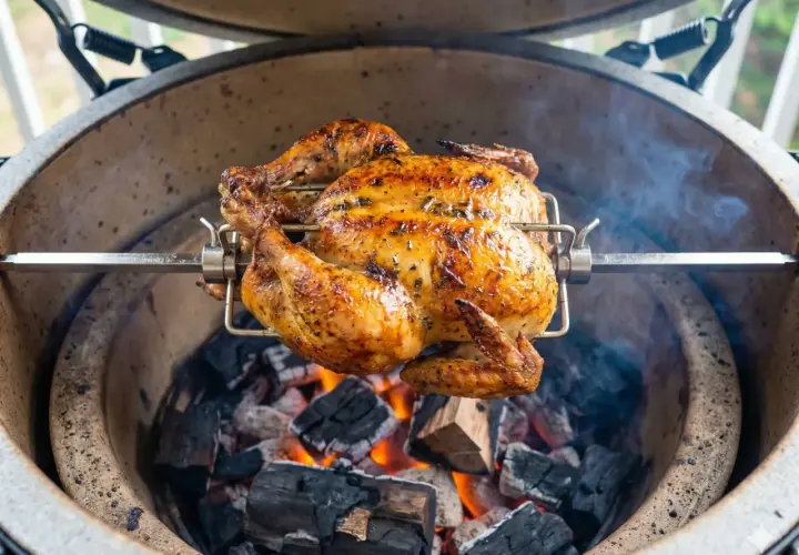 Hel kyckling grillas på rotisserie över glödande kol. En gyllene, saftig kyckling som doftar underbart.