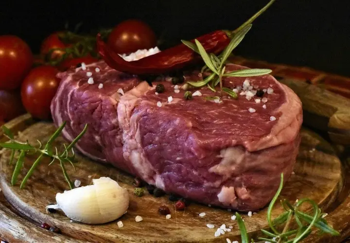 Rå entrecote, redo för grillen, med rosmarin, chili och vitlök. En perfekt grillad entrecote marinad väntar.