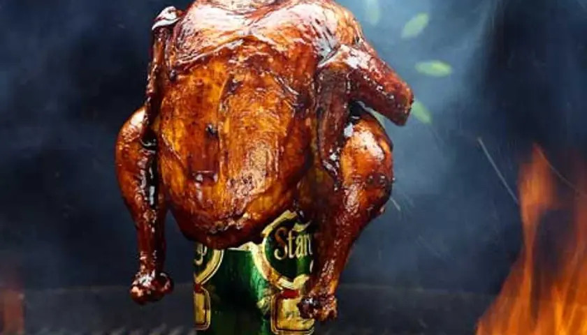 En saftig ölkyckling, perfekt grillad med gyllene skinn, står stolt på en ölburk. Rök och flammor skapar en dramatisk bakgrund.