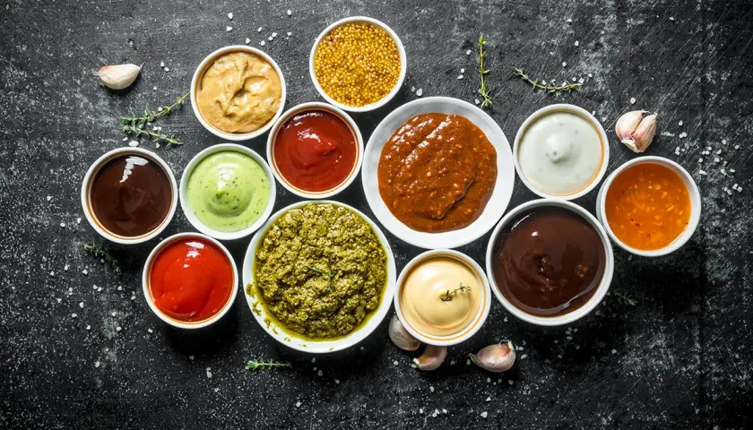 Olika såser i skålar, perfekt för att hitta inspiration till ditt eget barbequesås recept. Här finns allt från röd ketchup till grön pesto.