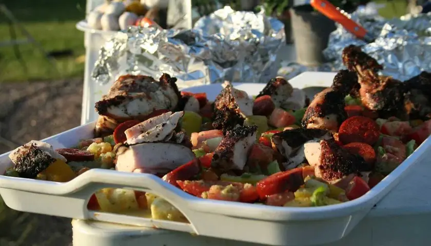 En stor vit form med grillad kyckling och en färgglad grönsakssallad, perfekt som salsa till grillat.