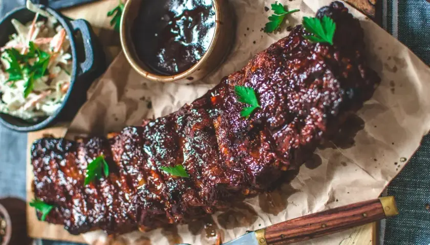 Saftiga ribs på grillen, glaserade och redo att avnjutas med en krispig coleslaw och en skål med BBQ-sås.