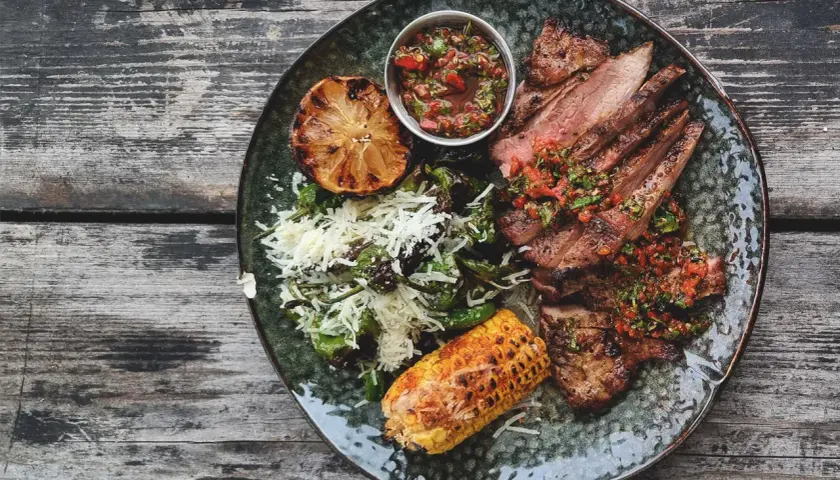 Skivad iberico-stek med perfekt temperatur, serverad med grillad majskolv, citron och en fräsch salsa.