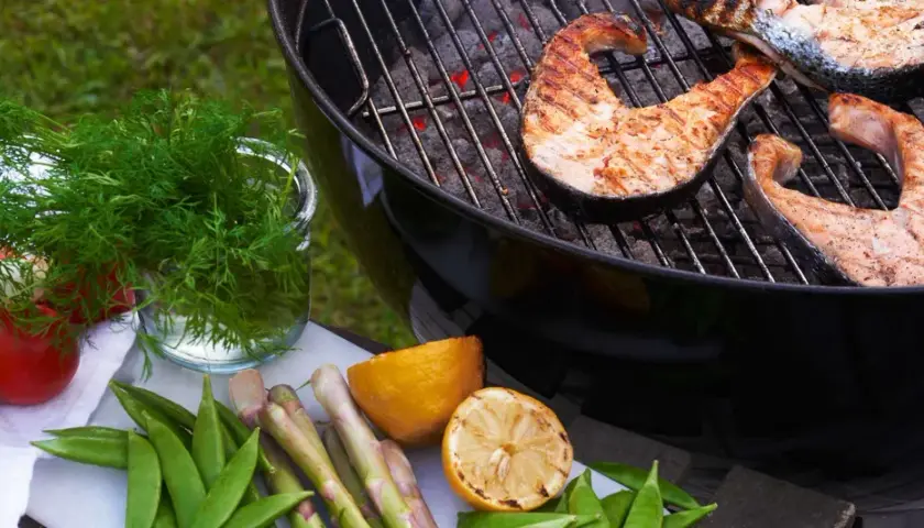 Grilla lax på kolgrill med färska grönsaker och citron. En härlig sommarmåltid.