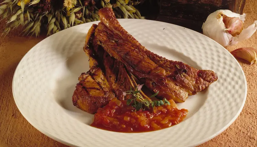 Saftiga, tjocka revben med en smakrik tomatsalsa och en vitlöksklyfta som dekoration.