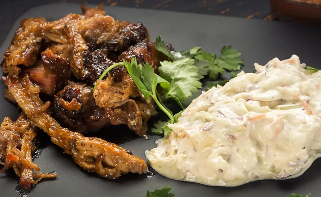 Saftigt pulled pork tid med krämig coleslaw, garnerat med färsk koriander. En klassisk kombination för en härlig måltid.