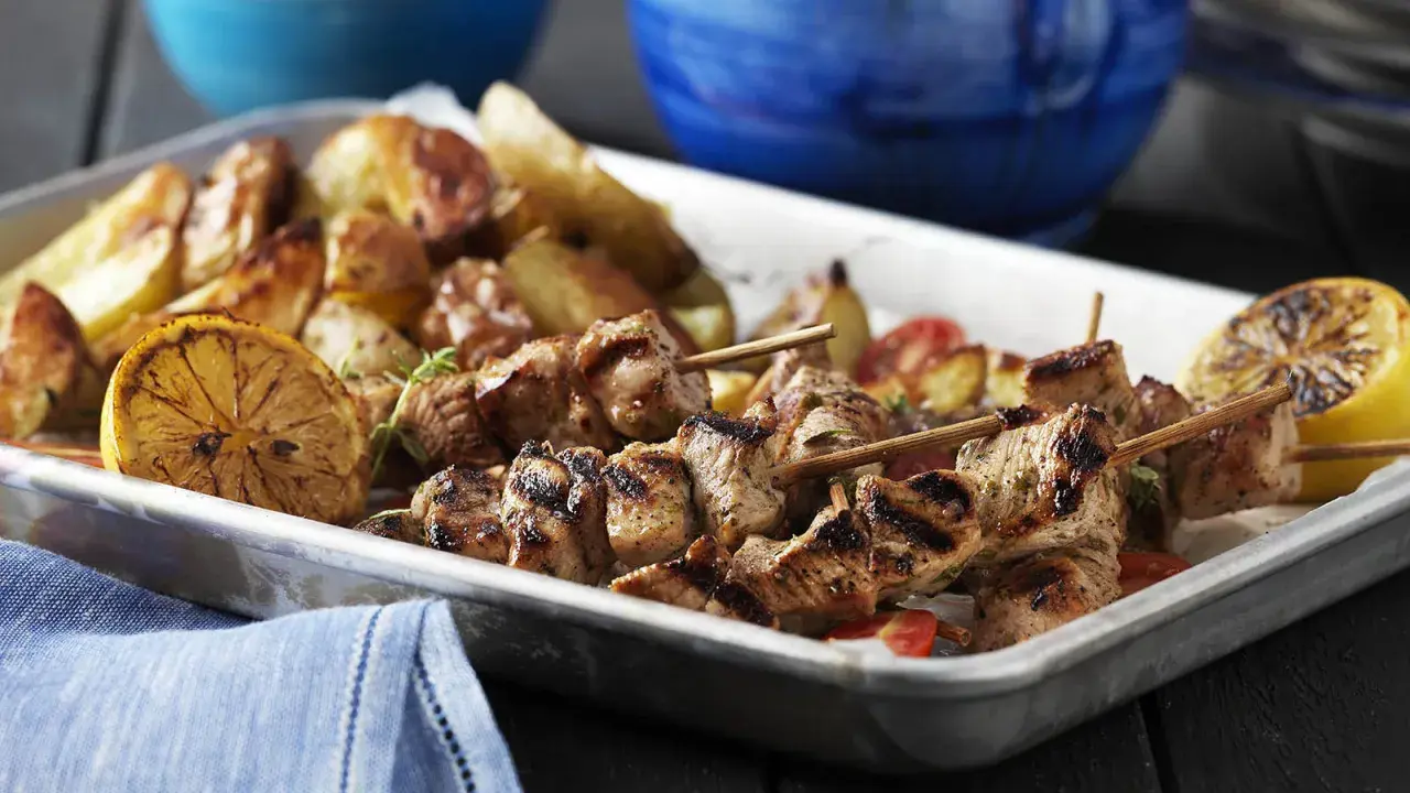 Grillade spett med fläskkött, rostade potatisar och citronklyftor. Perfekt med en god souvlaki krydda för extra smak.