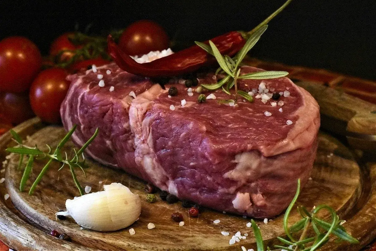 Rå entrecote, redo för grillen, med rosmarin, chili och vitlök. En perfekt grillad entrecote marinad väntar.