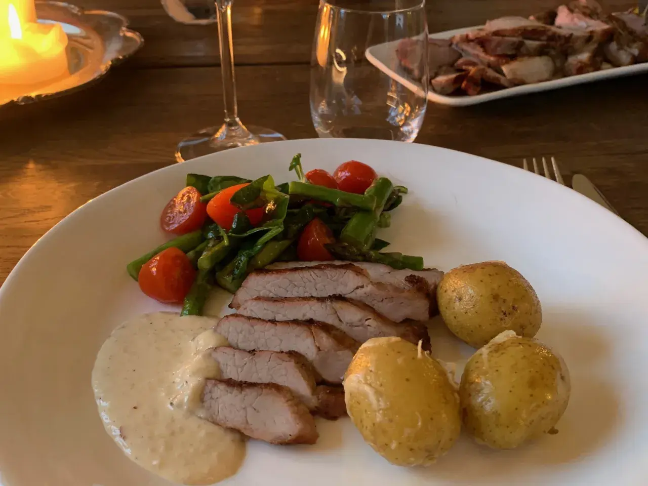 Skivad fläskfilé med krämig sås, sparris, körsbärstomater och småpotatis. Perfekt pluma innertemperatur för en lyckad middag.