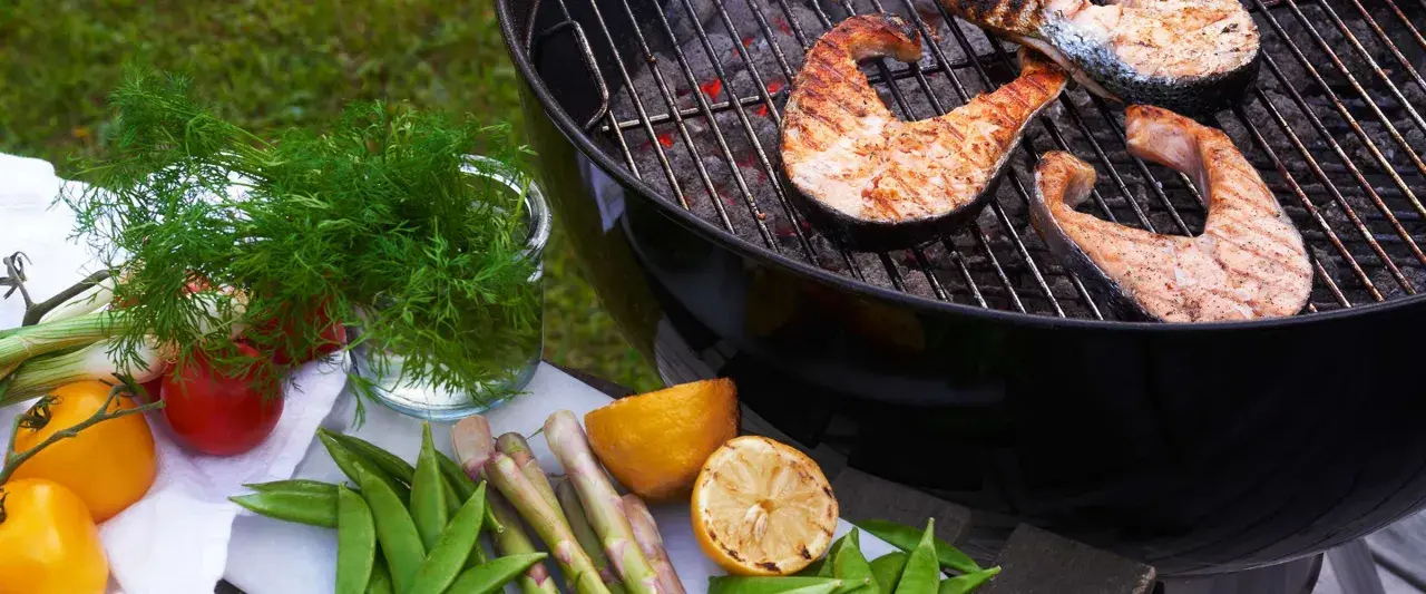 Grilla lax på kolgrill med färska grönsaker och citron. En härlig sommarmåltid.