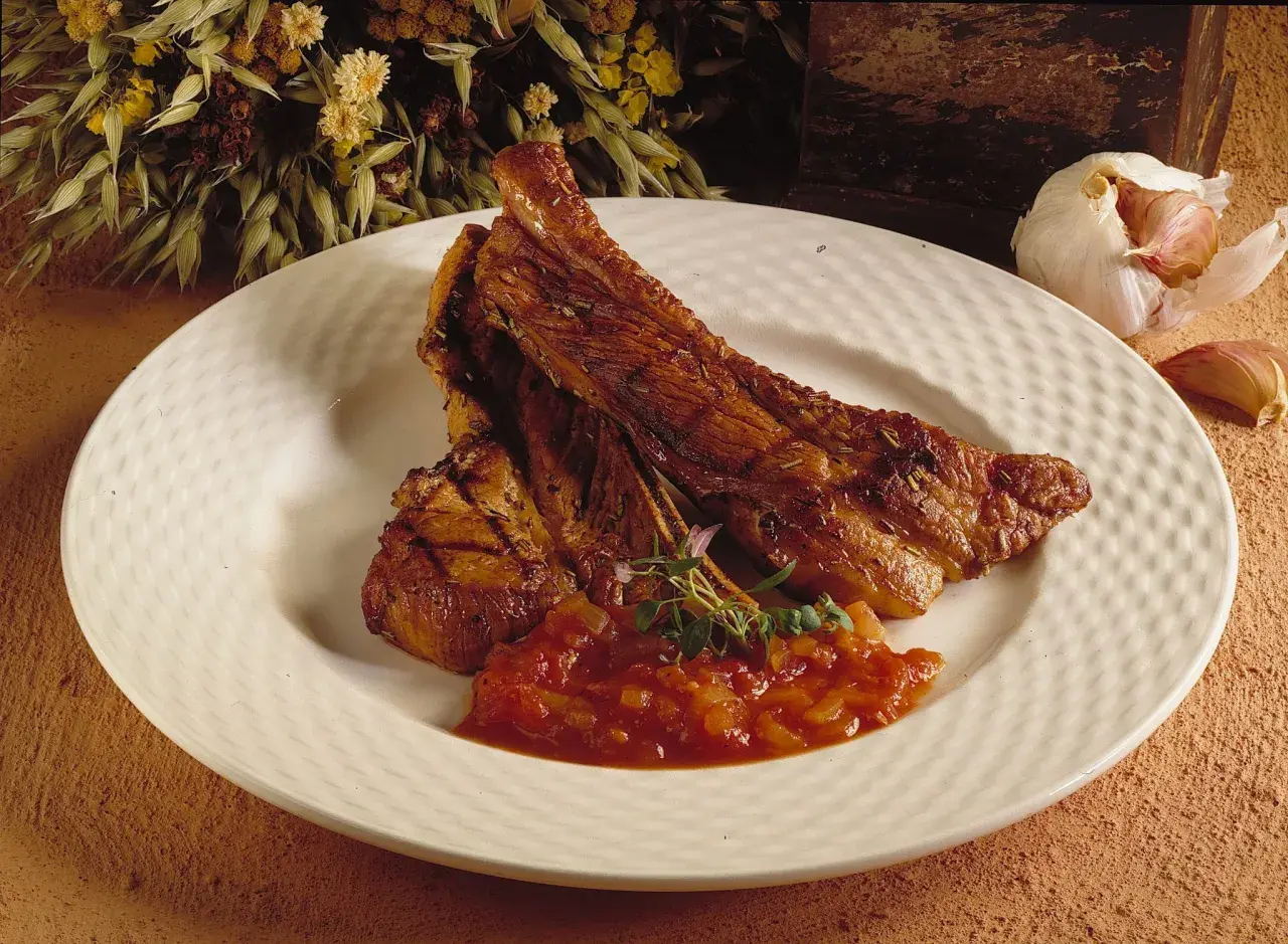Saftiga, tjocka revben med en smakrik tomatsalsa och en vitlöksklyfta som dekoration.