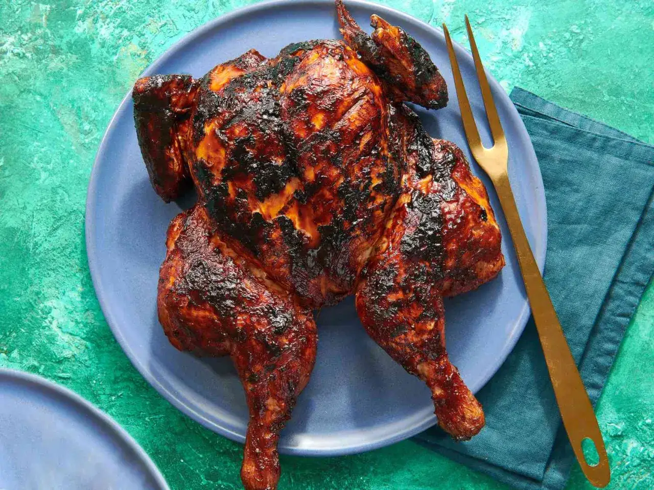 Helstekt kyckling med h&auml;rlig kycklingmarinad bbq, serverad p&aring; en bl&aring; tallrik med en guldig gaffel.