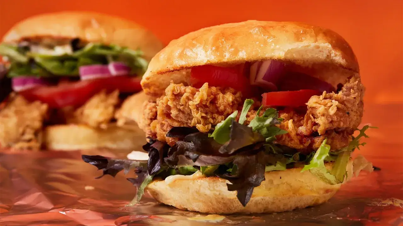 Två saftiga hamburgare med krispig kyckling, tomat, lök och sallad. En perfekt hamburgare smet för en hungrig mage.