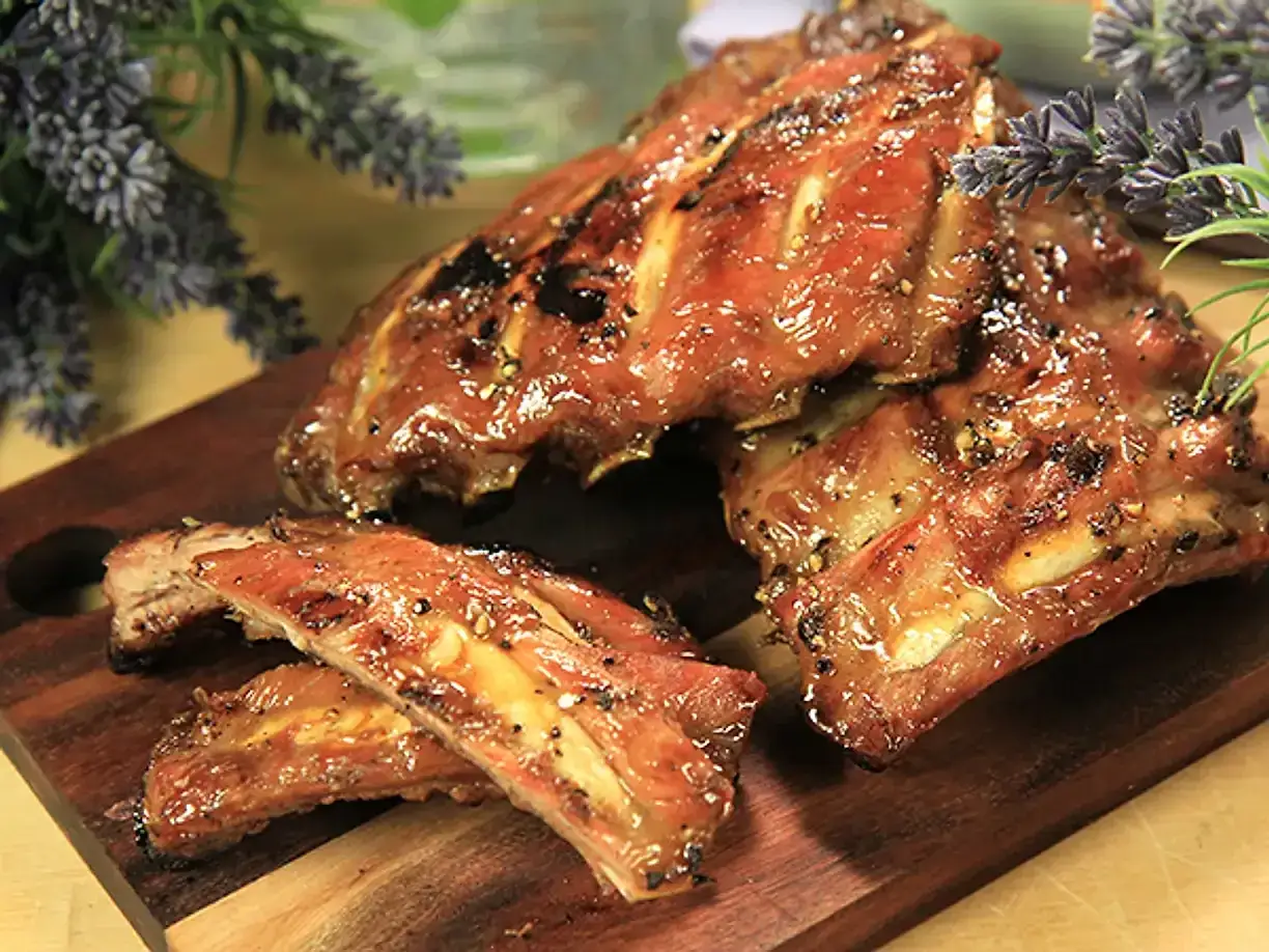 Saftiga kamben, perfekt grillade och glaserade, ligger upplagda p&aring; en tr&auml;sk&auml;rbr&auml;da. Doften av sommar och grillning sprider sig.