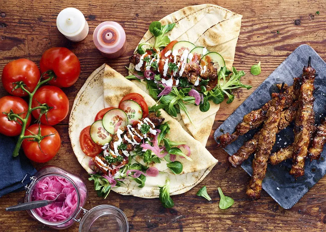 Grillad kyckling p&aring; spett och i pitabr&ouml;d, med tomater, gurka, sallad och picklad r&ouml;dl&ouml;k. Perfekt grillmarinad kyckling!