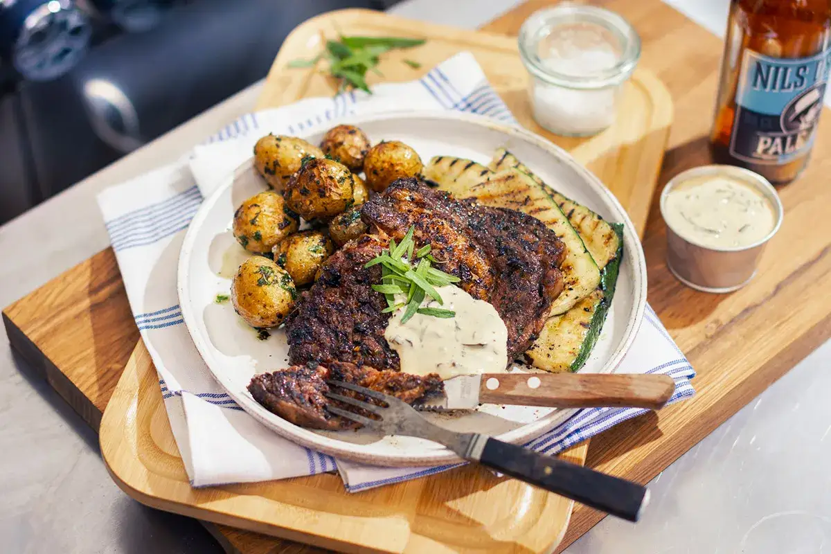 En saftig grillad entrecote med marinad, serverad med krispiga potatisar och grillad zucchini. En perfekt sommarmåltid.