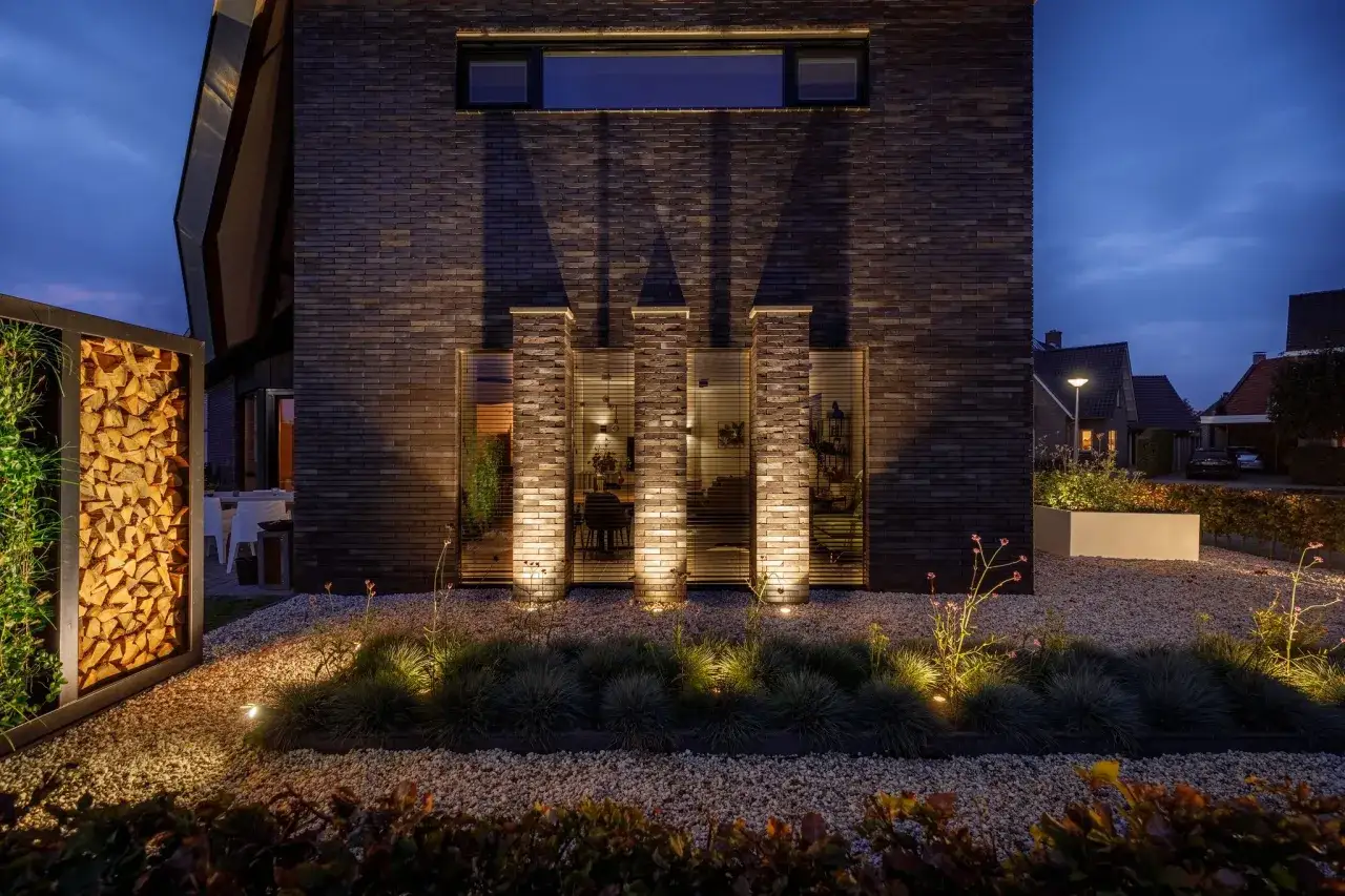 Modern villa med upplyst vedf&ouml;rvaring och stenlagd uppfart. Inspiration f&ouml;r en stilren och v&auml;lkomnande entr&eacute;.