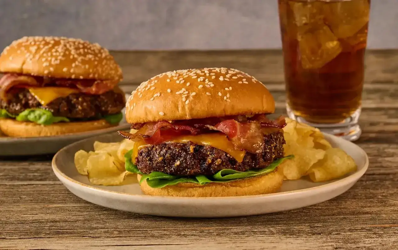 Saftig hamburgare med bacon, ost och sallad, serverad med chips och en l&auml;sk. En touch av worcestershires&aring;s ger extra smak.